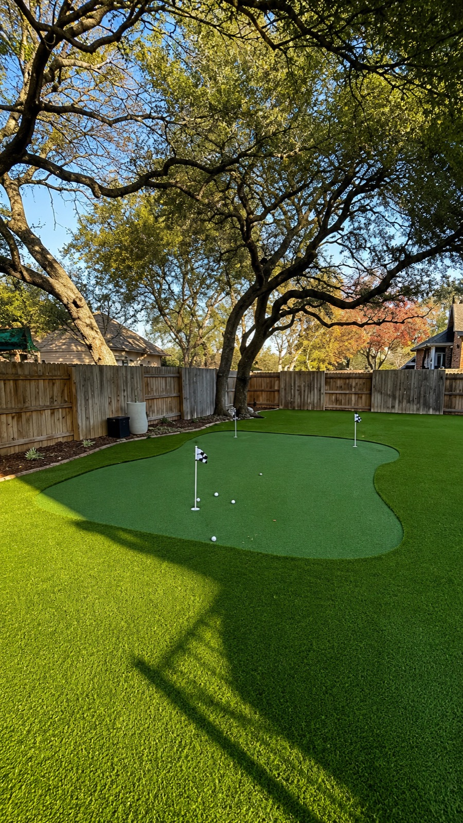 A backyard putting green built from artificial turf, with flags and golf balls